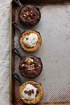 three chocolate cookies with whipped cream and walnuts on a baking sheet, ready to go into the oven