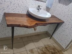 a bathroom sink sitting on top of a wooden table in front of a tiled wall