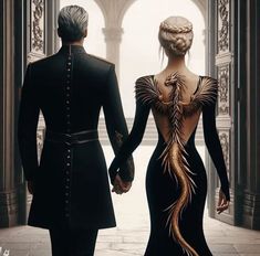 two people dressed in black holding hands and walking towards an archway with gold feathers on it