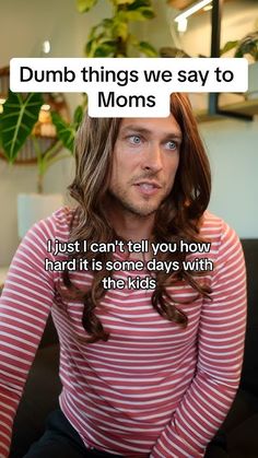 a man with long hair sitting on top of a couch next to a potted plant