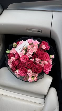 a bouquet of pink roses sitting in the back seat of a car, next to a steering wheel