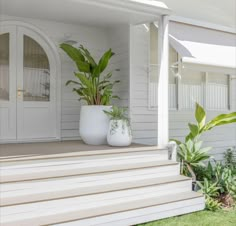 two large white vases sitting on top of a set of steps next to a house