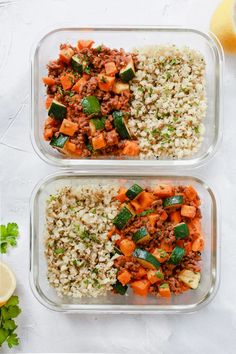 two glass containers filled with rice, meat and veggies next to lemon wedges