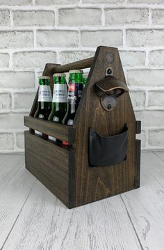 a wooden beer caddy with six bottles in it and a leather bottle opener on the side