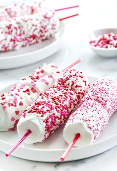 two white plates topped with pink and red sprinkles next to each other