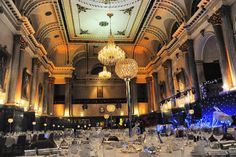 a large dining room with chandeliers and tables set for formal function at night