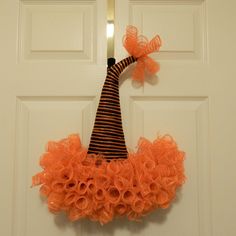 an orange and black wreath hanging on the front door to a white door with a striped top