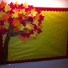 a tree made out of paper sitting on top of a wall next to a bulletin board