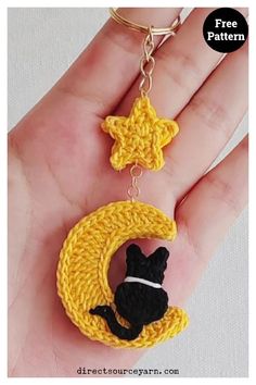 a crocheted keychain with a black cat on the moon hanging from it's side