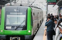 people are waiting on the platform to board a green train at a station in japan