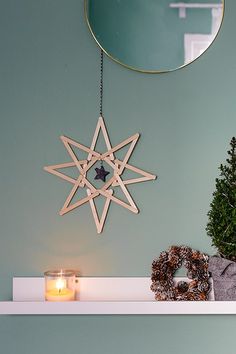 a wooden star hanging on the wall next to a candle and christmas tree in front of a mirror