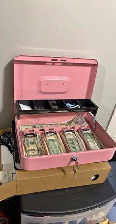 a pink suitcase filled with money sitting on top of a table