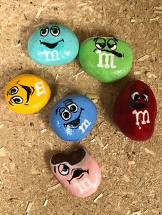 four painted rocks with m and m faces on them