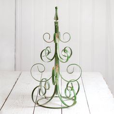 a green metal christmas tree on top of a wooden table