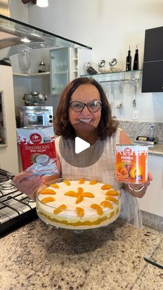 a woman holding up a cake with oranges on it