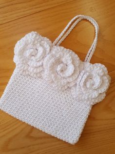 a crocheted purse with flowers on it sitting on top of a wooden table