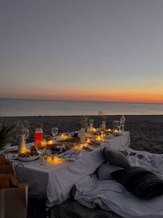 a dinner table set up on the beach at sunset