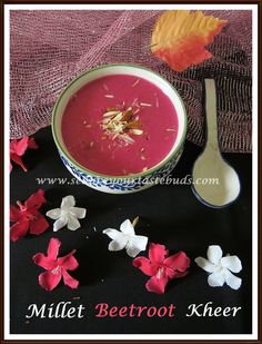 there is a bowl of soup and spoon next to it on the table with flowers