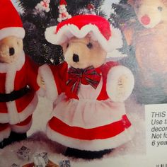 two teddy bears dressed as santa claus in front of a christmas tree