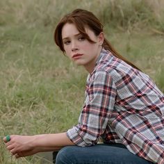 a woman sitting in the grass with her hand on her hip