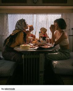 two women sitting at a table with food