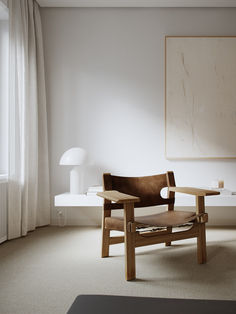 a wooden chair sitting in front of a window next to a painting on the wall