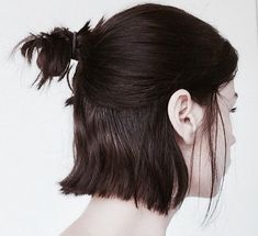 a woman with her hair pulled back in a pony tail style bun, looking to the side