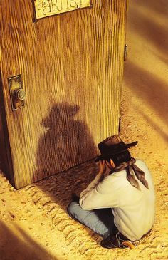 a man sitting on the ground in front of a wooden door with his shadow painted on it