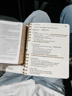 an open book sitting on top of a person's lap next to a pair of jeans