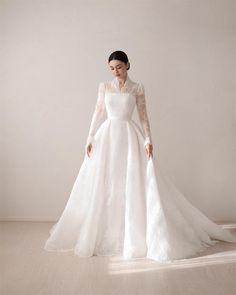 a woman in a white wedding dress standing on a wooden floor