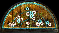 an old stained glass window with flowers in the center and blue, white and pink flowers on it