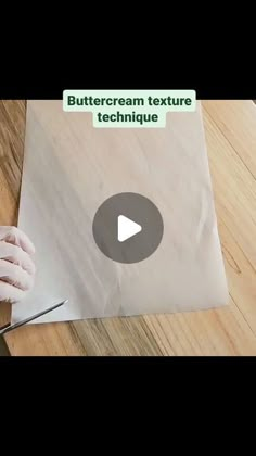 a person in white gloves cutting paper on top of a wooden table next to scissors