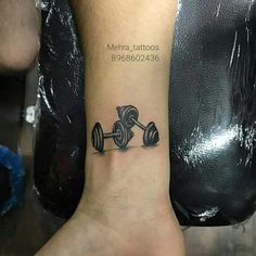 a tattoo on the foot of a person with dumbbells