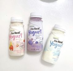 three yogurt bottles lined up next to each other on a white counter top