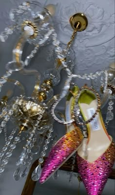 a pair of pink and gold shoes hanging from a chandelier in a room