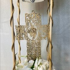 a cross made out of wood sitting on top of a table next to white flowers