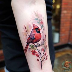 a red bird sitting on top of a branch with leaves and flowers around its neck