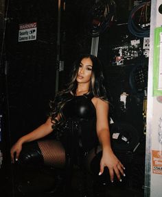 a woman sitting on top of a chair next to a wall filled with tires and wires