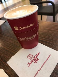 a cup of coffee sitting on top of a table next to some paper napkins