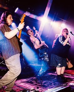 a group of people that are standing on a stage with guitars and microphones in their hands