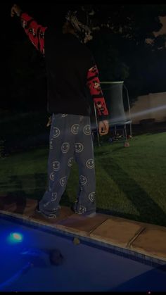 a man standing next to a swimming pool at night