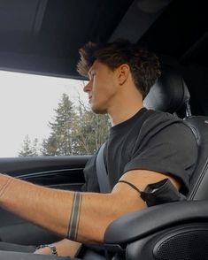 a man sitting in the driver's seat of a car using his cell phone