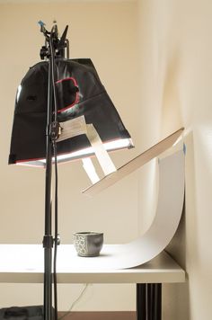 a black bag sitting on top of a white table next to a camera and light