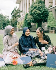 three women sitting on the grass laughing