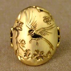 a gold ring with a bird and flowers on it