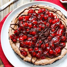 a cherry pie with chocolate drizzle on top is sitting on a white plate