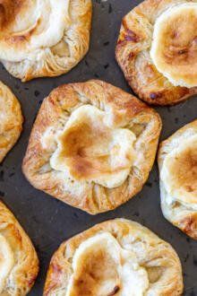 several pastries sitting on top of a baking pan covered in cheese and banana slices