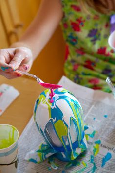 a woman is painting an easter egg with colorful paint