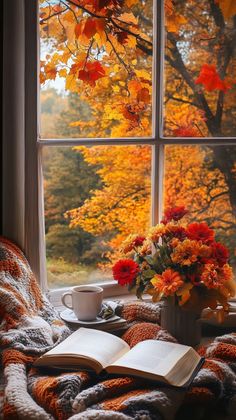 an open book sitting on top of a window sill next to a cup of coffee