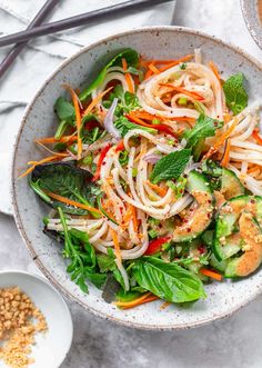 a bowl filled with noodles and vegetables next to some chopsticks on the side